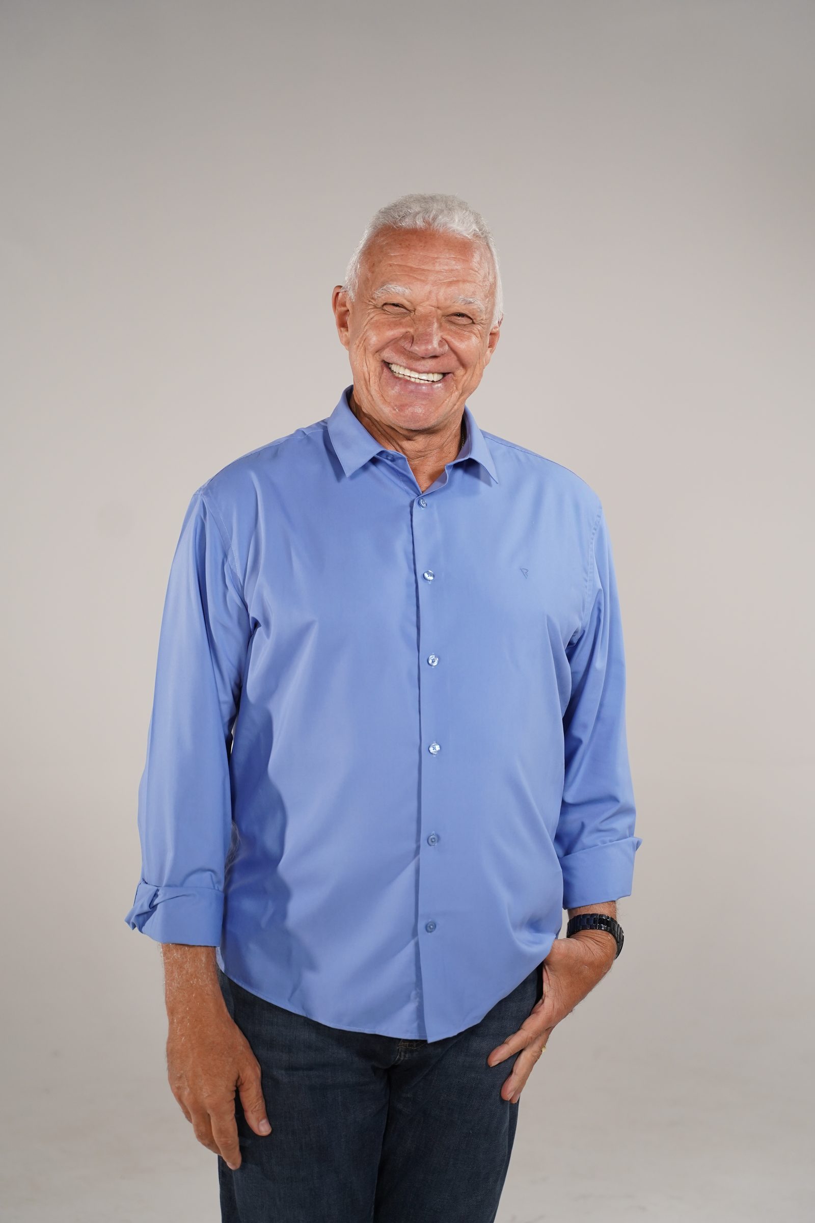 Zé Humberto em pé, de camisa azul, sorrindo